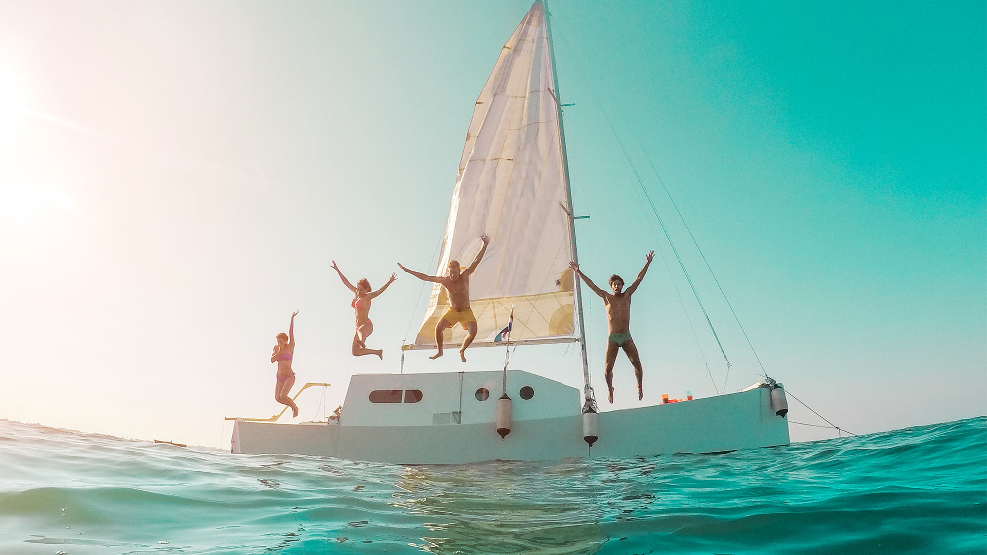 happy-crazy-friends-diving-from-sailing-boat-into-2021-09-03-13-36-52-utc
